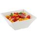 A white Tablecraft melamine bowl filled with salad, tomatoes, onions, and peppers.