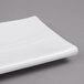 A Tablecraft white rectangular melamine tray with a curved edge.