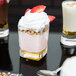 A square Arcoroc shot glass filled with a dessert and whipped cream.