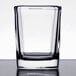 An Arcoroc square shot glass on a reflective surface.