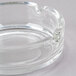 A clear Arcoroc glass ashtray with a small hole in the center.