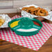 A green HS Inc. polypropylene server with a bowl of onion rings and a bowl of sauce on a table with a red and white checkered tablecloth.