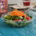 A salad in a Dart clear plastic bowl with a fork.