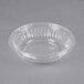 A Dart clear plastic bowl on a gray surface.
