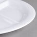 A close-up of a Carlisle white melamine plate with 3 compartments.