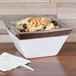 A Cal-Mil stainless steel square bowl filled with pasta and olives on a table in a salad bar.