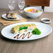 A Thunder Group Blue Jade oval melamine platter with sushi and other food on it on a table.