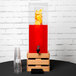 A Cal-Mil bamboo beverage dispenser with red liquid and orange slices in it on a wooden base.