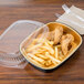 A Durable Packaging black and gold aluminum foil container with chicken and french fries with a clear plastic dome lid.