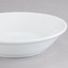 An Arcoroc white china bowl on a gray surface.