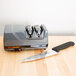 A knife and a Edgecraft Chef's Choice electric knife sharpener on a table.