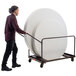 A man using the National Public Seating Round Folding Table Dolly to move a large round table.