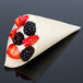 A Cal-Mil wooden serving cone filled with fruit.
