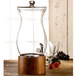 An American Atelier glass beverage dispenser with a wood stand and spigot.