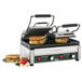 A Waring Panini Sandwich Grill with two sandwiches cooking inside.