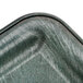 A close-up of a green plastic tray with a black and grey marbled surface.