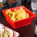 A red container with chips on a table in a Mexican restaurant.