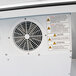 A close-up of a white vent with warning signs on a Turbo Air ice merchandiser.