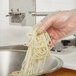 A person using a Nemco Fine Cut Garnish Cutter to make noodles.