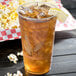 A Bare by Solo RPET disposable plastic cup filled with ice tea and a lemon wedge with popcorn on the side.