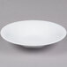 A CAC Super Bright White Coupe Porcelain bowl on a gray surface.