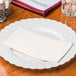 A white plate with a Hoffmaster ivory paper napkin on it.