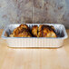 A Durable Packaging foil pan with cooked chicken on a table.