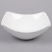 A white American Metalcraft square stoneware bowl with a curved edge on a white surface.