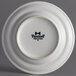 A white Tuxton Concentrix china plate with black text reading "Tuxton" on it.
