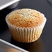 A muffin in a White Fluted Baking Cup on a pan.