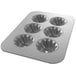 A silver Chicago Metallic 6 compartment mini cake pan with swirl designs in each cavity.