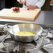 A chef using a Vollrath Miramar French Omelet Pan to cook in a kitchen.