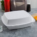 A white Dart foam container with 3 compartments on a table.
