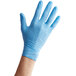 A hand wearing a blue Noble Products powder-free disposable nitrile glove.