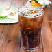 A clear plastic Bahama tumbler filled with ice tea on a wooden table.