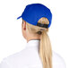 A woman with a ponytail wearing a royal blue Headsweats 5-panel cap with a terry sweatband.
