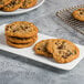 A plate of chocolate chip cookies with a stack of cookies on a white plate.