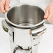 A person holding a stainless steel water pan for a Vollrath marmite.