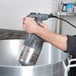 A person using a Robot Coupe immersion blender to mix a large pot.