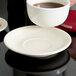 A Tuxton Eggshell china cappuccino saucer with a cup of coffee on it.