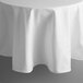 A white Intedge round tablecloth with hemmed edges on a table.