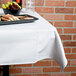 A white Intedge square tablecloth on a table with food on it.