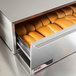 An APW Wyott metal box with a drawer full of hot dog buns.