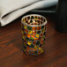 A Sterno Earthtone Votive Glass candle holder with a lit candle inside.