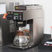 A Bunn commercial automatic coffee maker on a counter with a glass coffee pot.