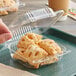 A hand holding a Durable Packaging clear plastic container with pastries inside.