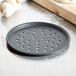 An American Metalcraft round black hard coat anodized aluminum pizza pan with holes in it.