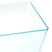 A clear plastic cube bowl with a green edge.