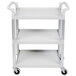 A speckled gray three shelf utility cart with metal handles on wheels.