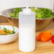 A clear Tablecraft squeeze bottle next to a bowl of salad.